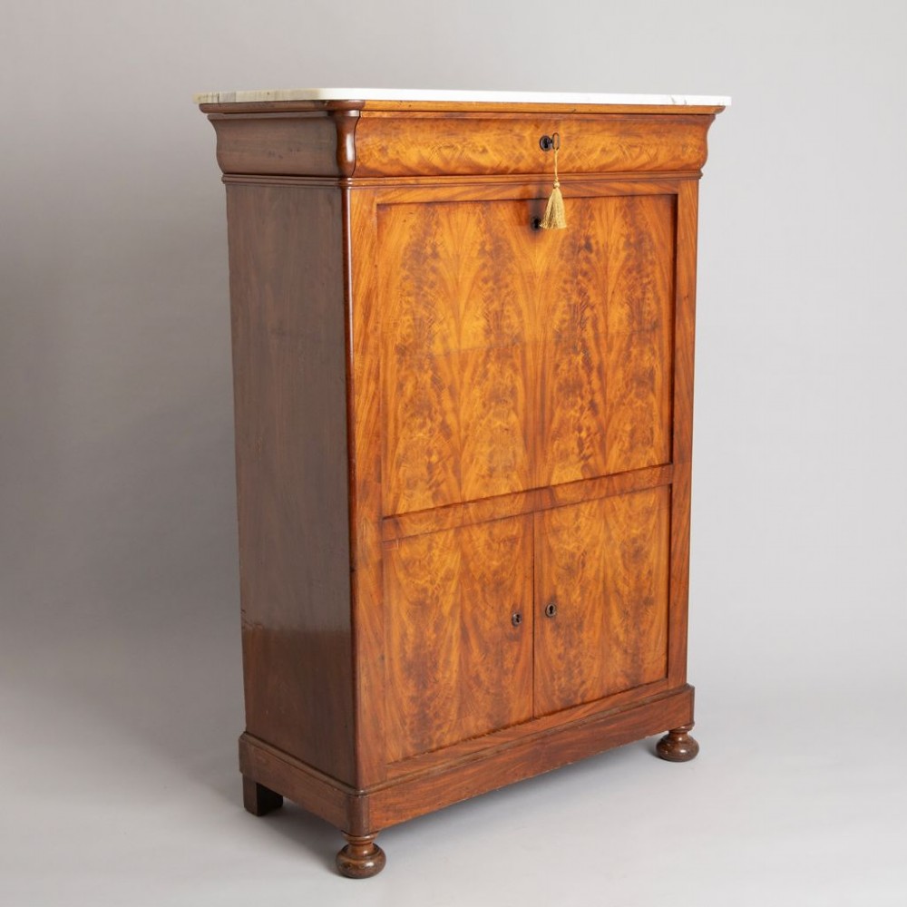 A 19th-century French Louis Philippe flame mahogany secretaire a abattant featuring a white marble top, upper frieze drawer, drop-front writing flap, and lower double doors. View II