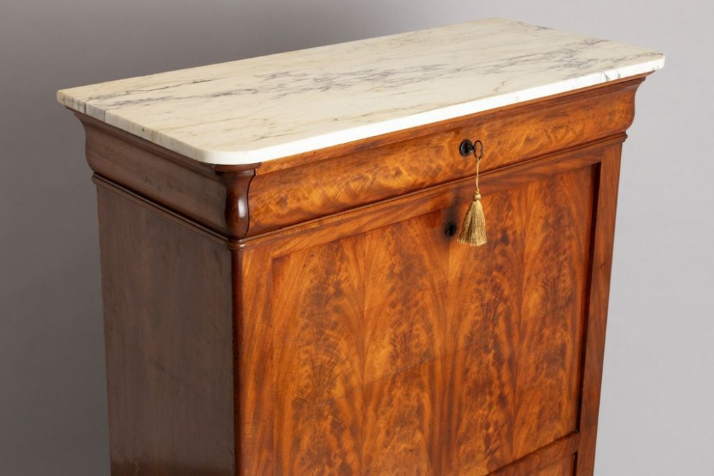 A 19th-century French Louis Philippe flame mahogany secretaire a abattant featuring a white marble top, upper frieze drawer, drop-front writing flap, and lower double doors. View V