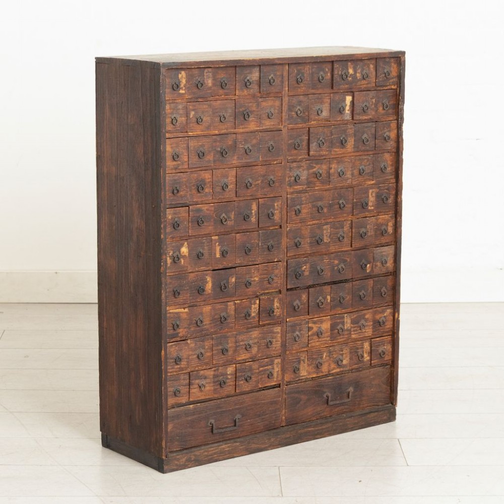 A tall dark timber Japanese apothecary cabinet featuring multiple small rectangular drawers with iron ring pulls above two wider base drawers. View II