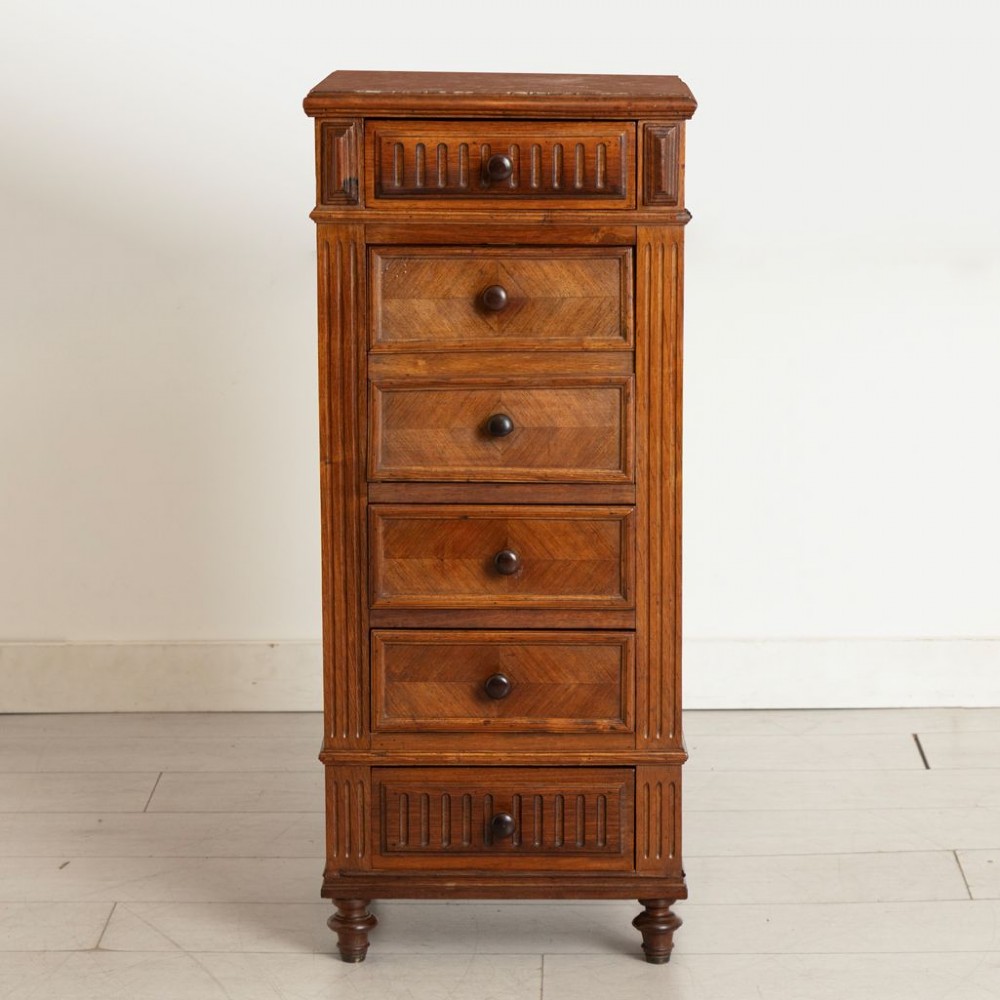 An antique French rosewood bedside chest featuring six drawers, chevron parquetry veneer, fluted side columns, turned feet, and an inset brown marble top. View II
