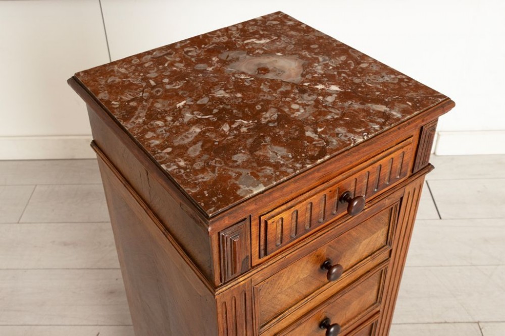 An antique French rosewood bedside chest featuring six drawers, chevron parquetry veneer, fluted side columns, turned feet, and an inset brown marble top. View III
