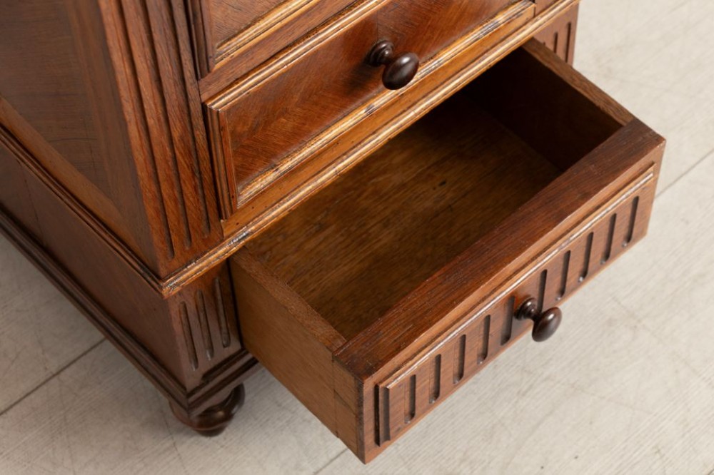 An antique French rosewood bedside chest featuring six drawers, chevron parquetry veneer, fluted side columns, turned feet, and an inset brown marble top. View IV