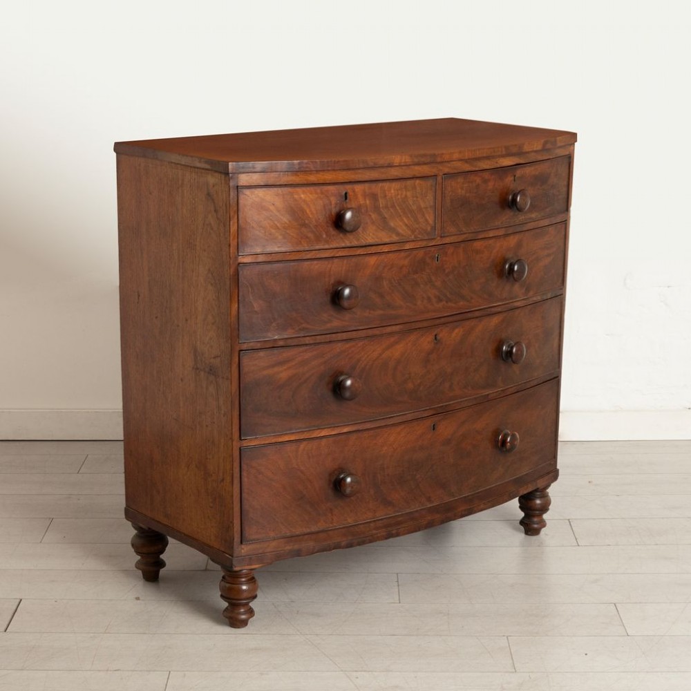A Victorian mahogany bowfront chest of drawers featuring two short upper drawers and three long lower drawers with turned wooden knobs and turned feet. View II