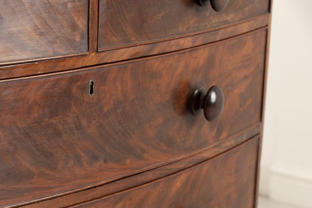 A Victorian mahogany bowfront chest of drawers featuring two short upper drawers and three long lower drawers with turned wooden knobs and turned feet. View III