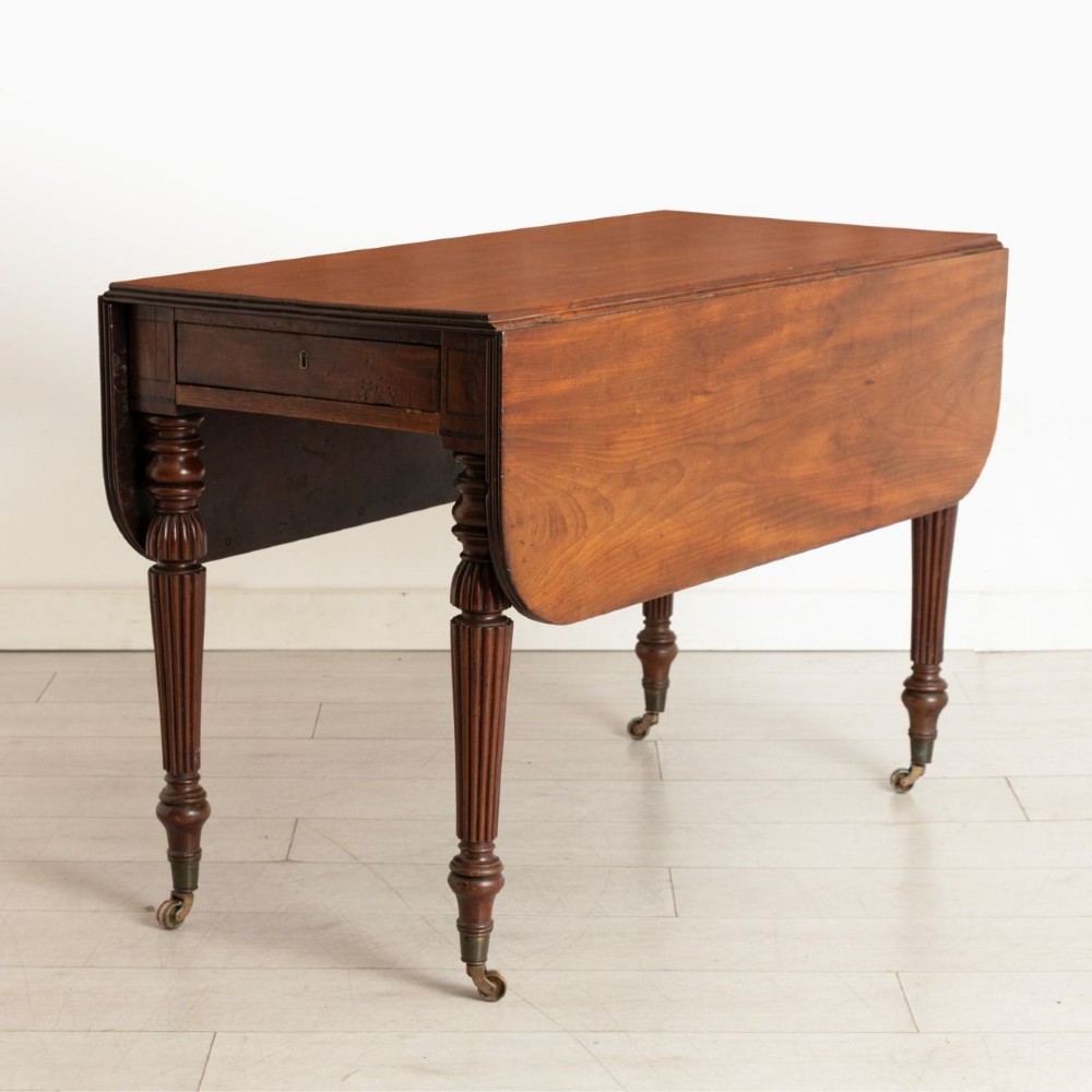 A William IV mahogany Pembroke table with two drop-leaf flaps, a single frieze drawer, reeded turned legs, and brass castors.