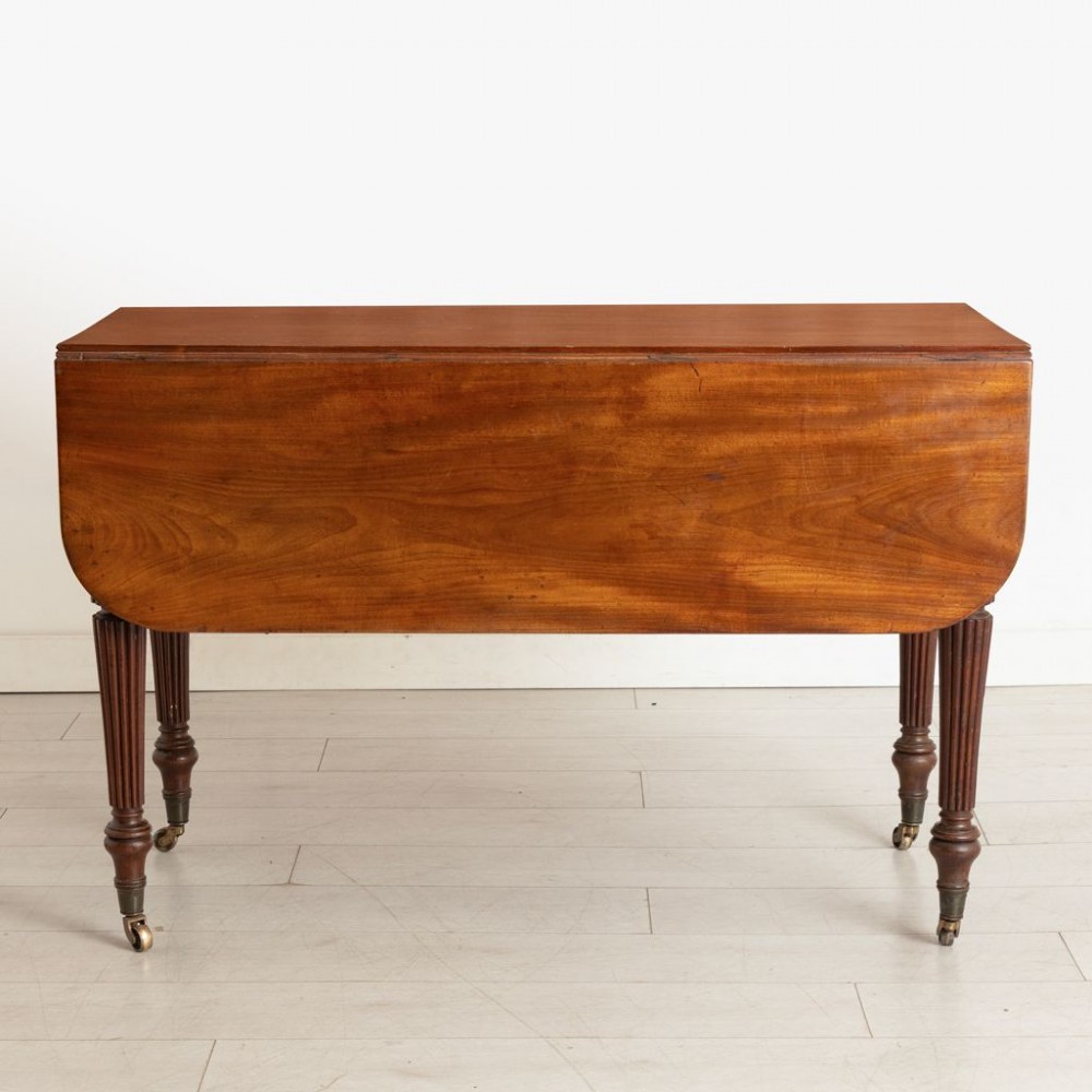 A William IV mahogany Pembroke table with two drop-leaf flaps, a single frieze drawer, reeded turned legs, and brass castors. View II