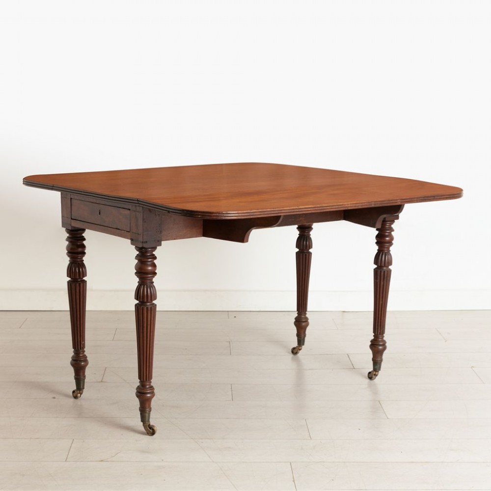 A William IV mahogany Pembroke table with two drop-leaf flaps, a single frieze drawer, reeded turned legs, and brass castors. View III