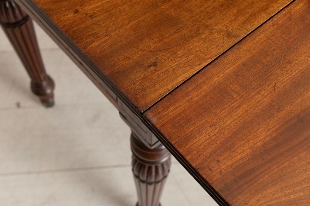 A William IV mahogany Pembroke table with two drop-leaf flaps, a single frieze drawer, reeded turned legs, and brass castors. View IV