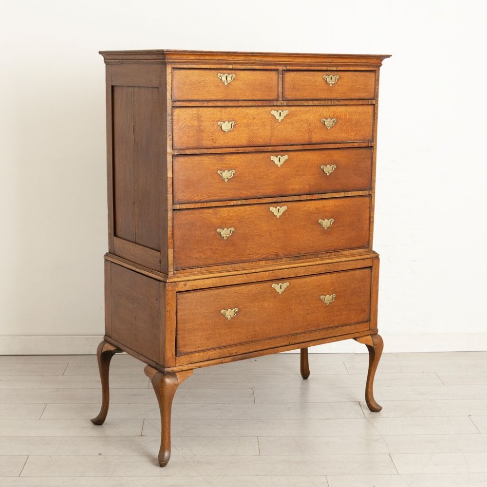 An 18th-century oak chest on stand featuring multiple graduated drawers with brass hardware, raised on four shaped cabriole legs. View II