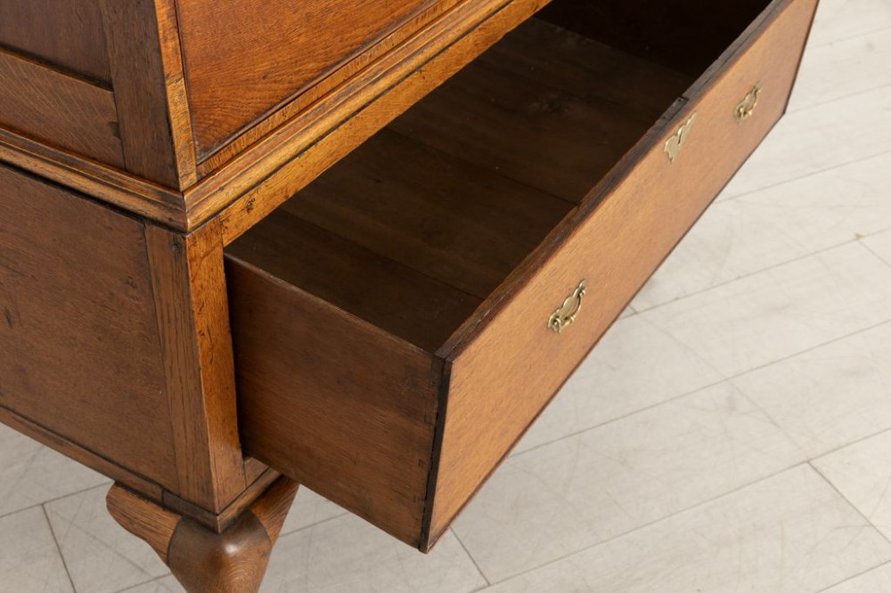 An 18th-century oak chest on stand featuring multiple graduated drawers with brass hardware, raised on four shaped cabriole legs. View III