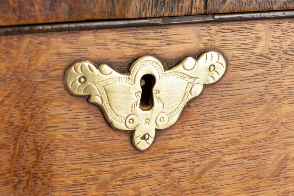 An 18th-century oak chest on stand featuring multiple graduated drawers with brass hardware, raised on four shaped cabriole legs. View IV