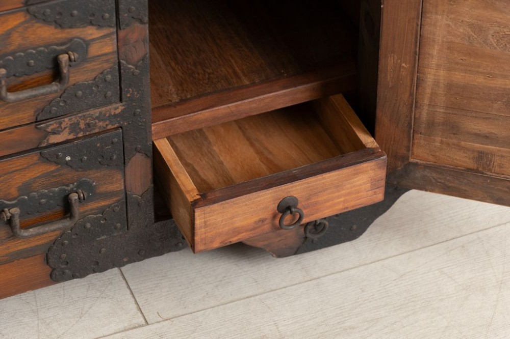 An antique Japanese zelkova wood chest of drawers featuring dark iron corner brackets, lock plates, drop handles, and integrated wooden wheels at the base. View III