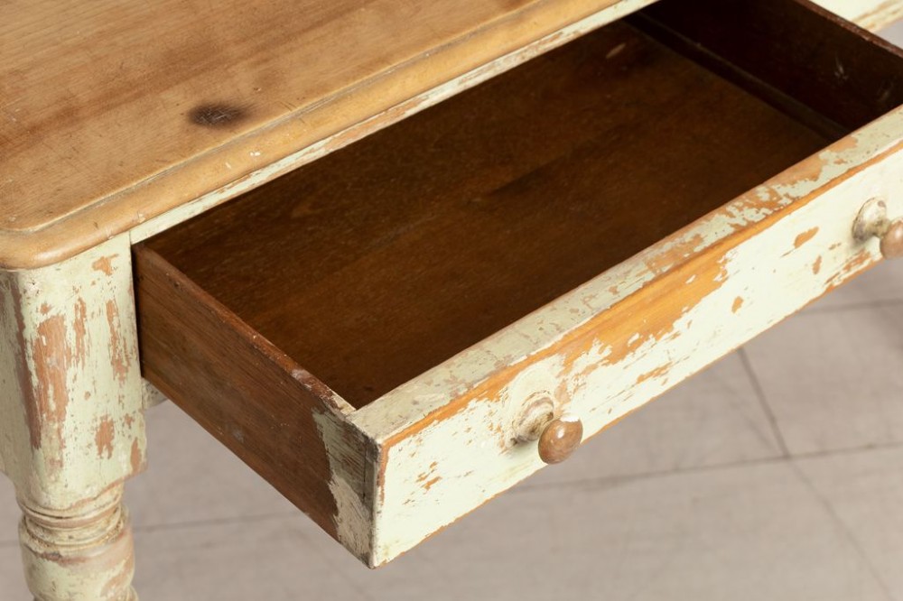 A 19th-century birch writing table with a polished natural timber top, two drawers with wooden knobs, distressed off-white painted turned legs, and brass castors. View III