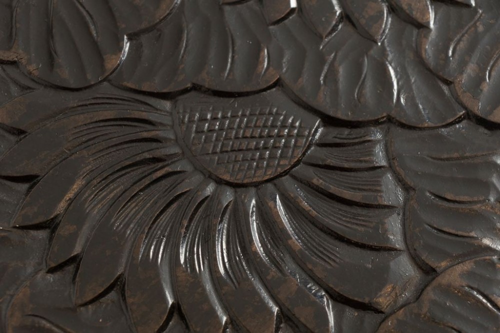 A dark-stained wooden side table featuring a circular top and three outward-curving legs detailed with relief floral carvings and a small lower shelf. View III