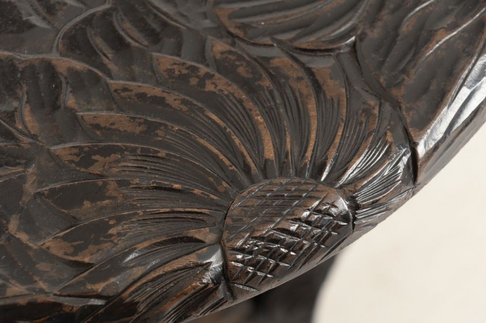 A dark-stained wooden side table featuring a circular top and three outward-curving legs detailed with relief floral carvings and a small lower shelf. View IV
