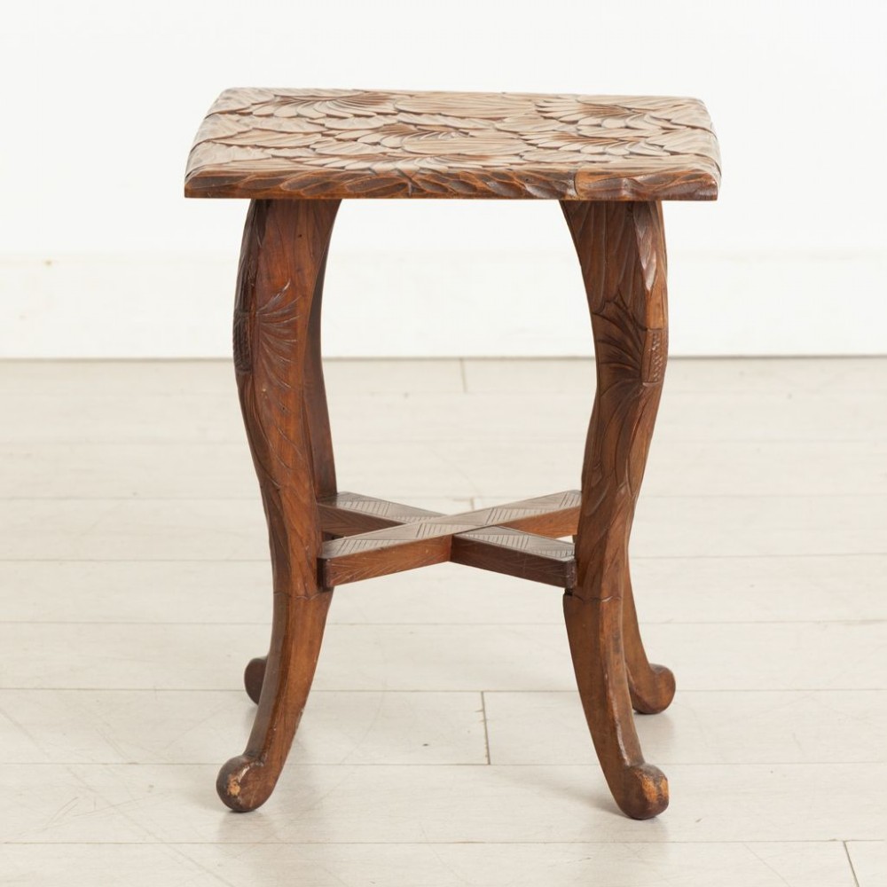 An antique hand-carved wooden side table featuring floral chrysanthemum motifs on the square top and curved legs joined by an X-stretcher.