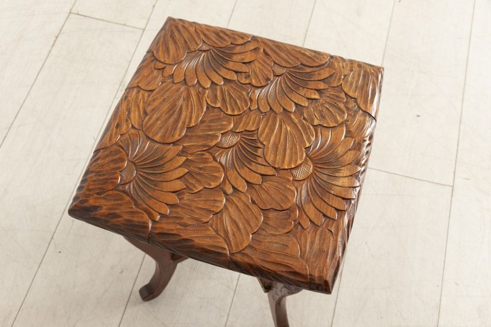 An antique hand-carved wooden side table featuring floral chrysanthemum motifs on the square top and curved legs joined by an X-stretcher. View IV