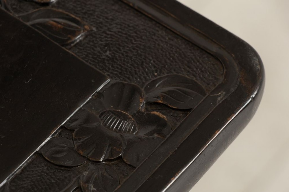 A tall ebonised wooden plant stand featuring carved floral detailing on the square top surface, slender curved legs, and an lower tier shelf. View III