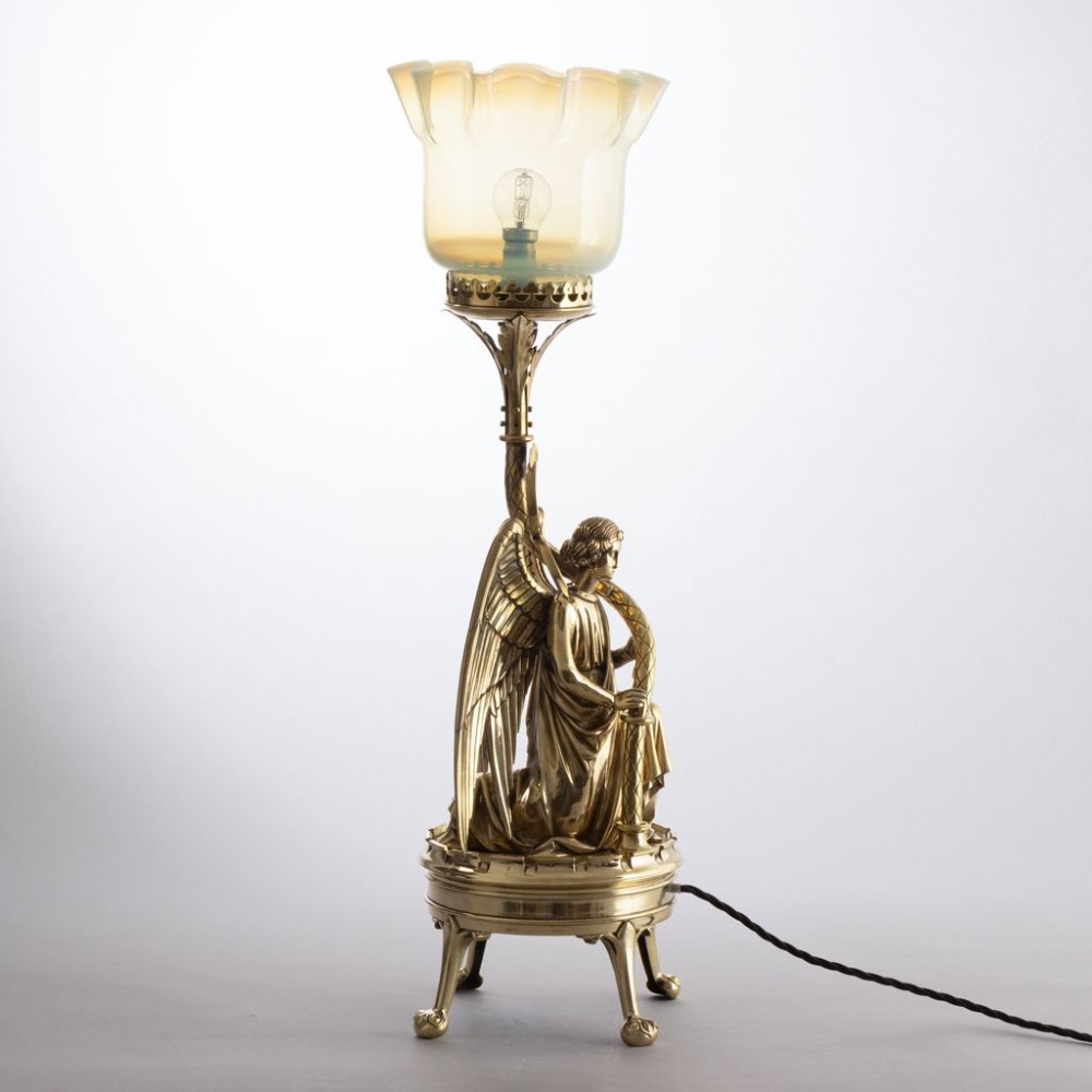 A late Victorian Gothic Revival brass table lamp featuring a detailed kneeling angel figure supporting a frilled vaseline glass shade. View V