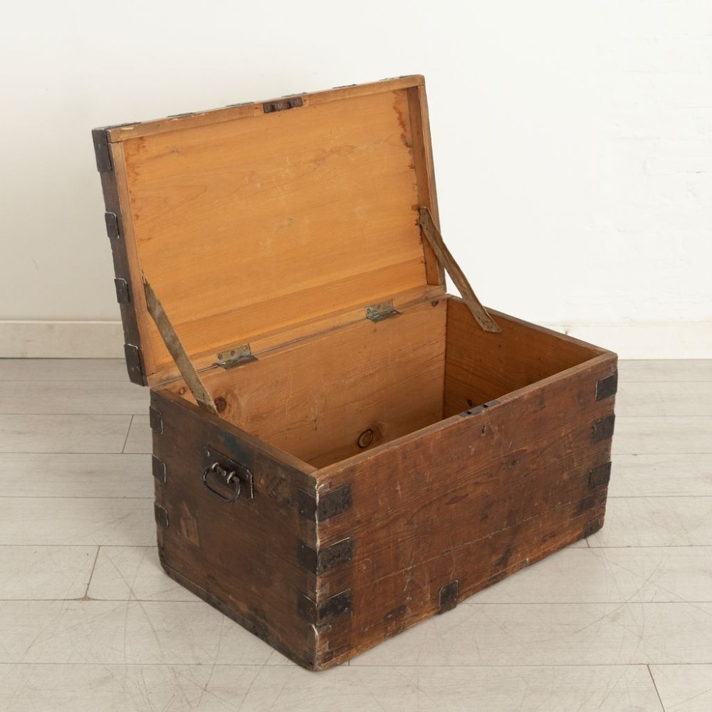 A rectangular Victorian pine travel trunk featuring iron corner straps, a front keyhole, and stencilled black text across the top lid. View III