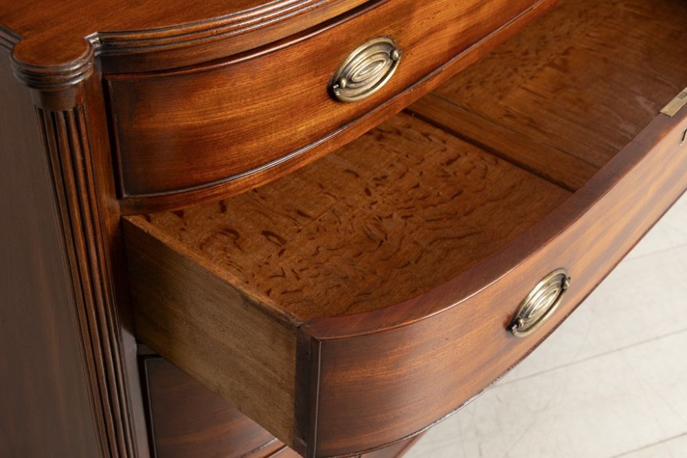 A Regency period mahogany bow-fronted chest featuring four graduated drawers with brass oval handles and reeded side columns. View III