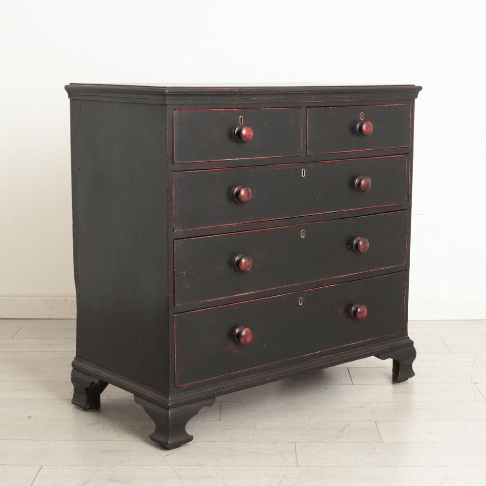 A 19th-century two-over-three chest of drawers with a distressed black painted finish over red undercoats, featuring turned wooden knobs and brass escutcheons. View II