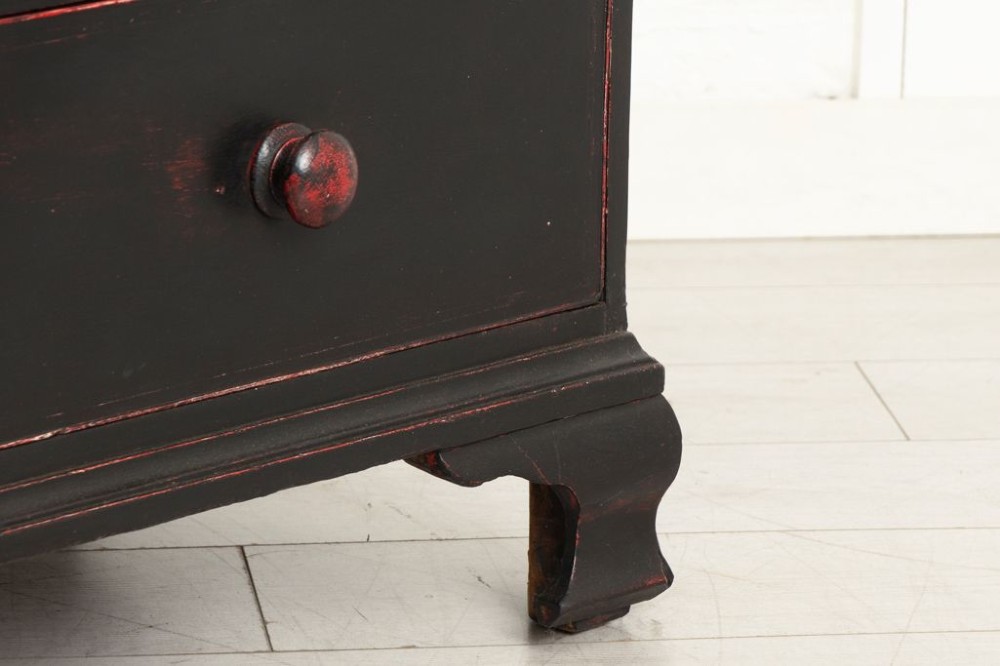 A 19th-century two-over-three chest of drawers with a distressed black painted finish over red undercoats, featuring turned wooden knobs and brass escutcheons. View III