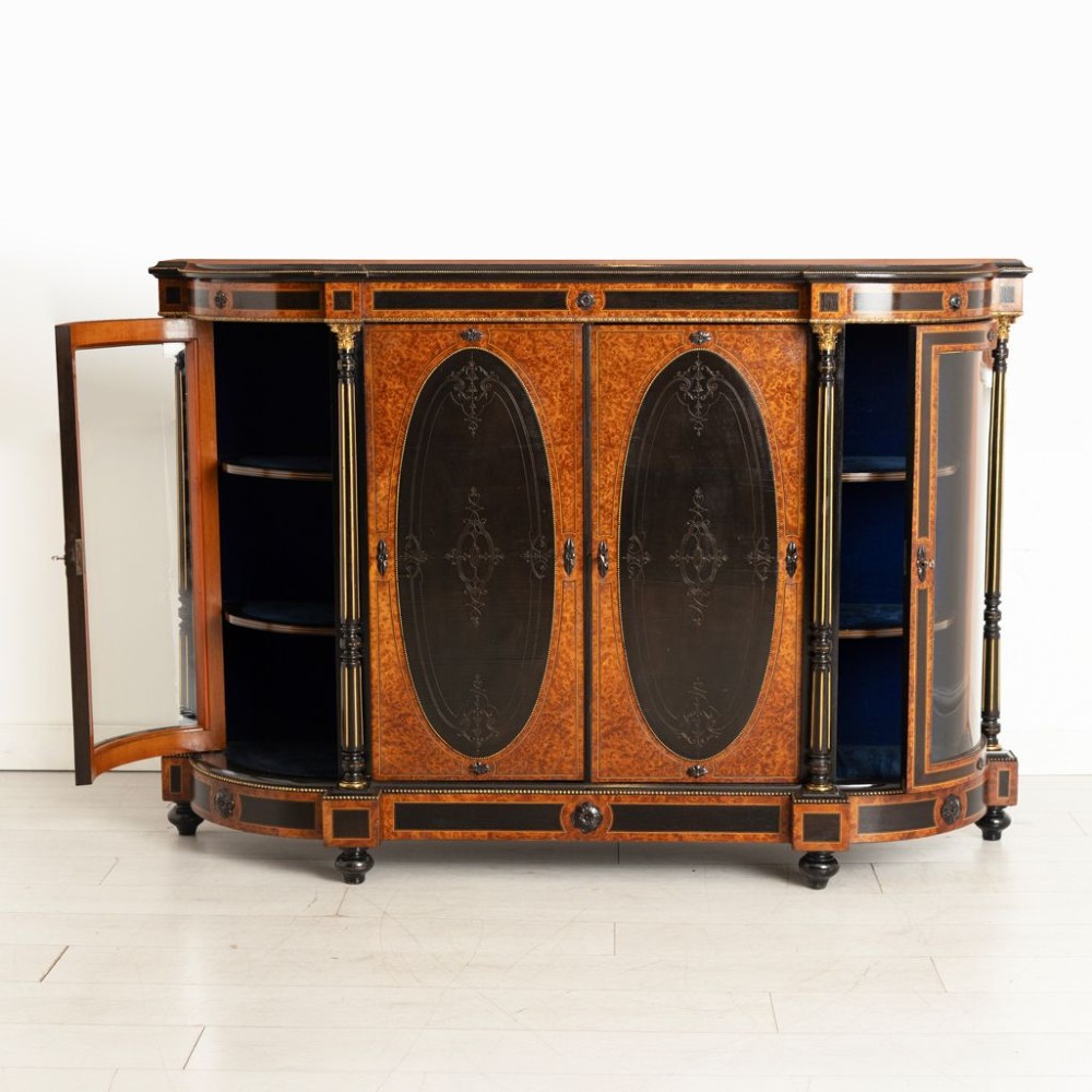 An early Victorian credenza crafted in figure-grained amboyna wood with ebony borders, featuring two central oval-panelled doors flanked by curved glazed side doors and gilt column accents. View III