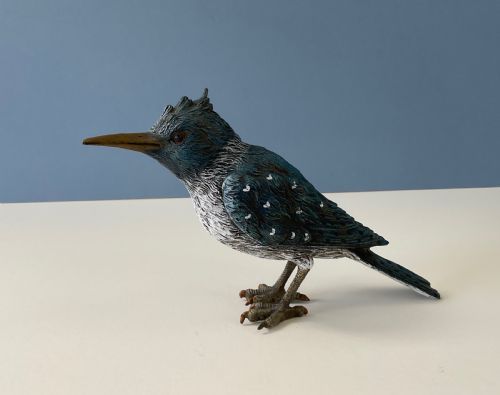 fig 1. An antique cold-painted bronze figure of a crested kingfisher bird with blue, white, and bronze details standing on two legs.