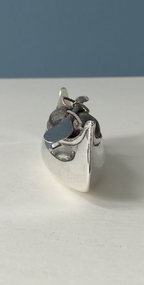 fig 1. An antique silver canoe-shaped pin cushion featuring a central dark fabric cushion and miniature oar details.
