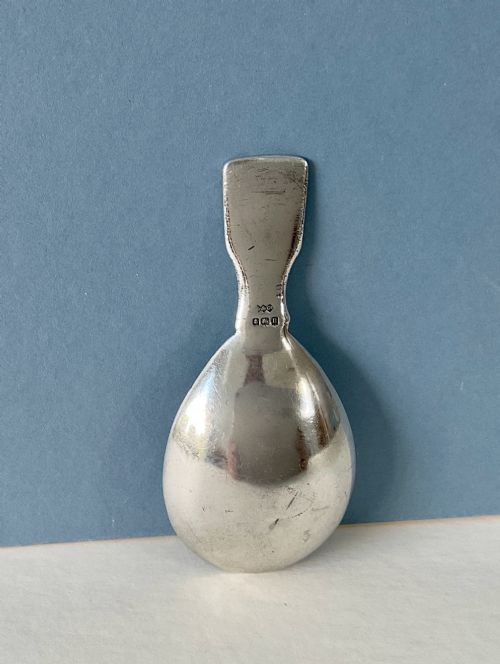 fig 1. An antique sterling silver caddy spoon featuring a teardrop bowl and flat handle decorated with geometric basketweave engraving.
