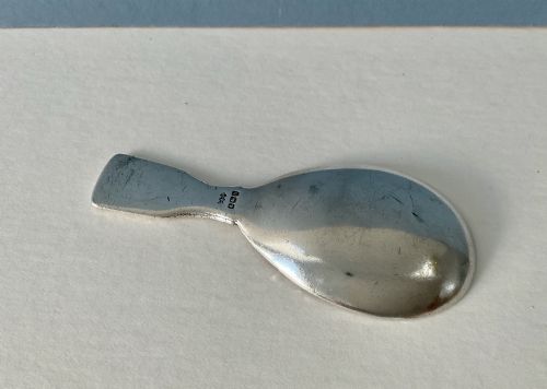 fig 2. An antique sterling silver caddy spoon featuring a teardrop bowl and flat handle decorated with geometric basketweave engraving.