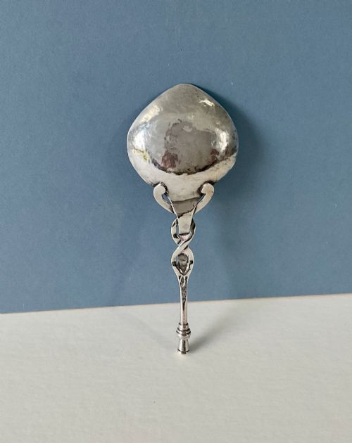 fig 1. An Arts and Crafts sterling silver caddy spoon featuring a hand-hammered bowl and an intertwined stem handle.