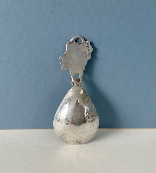 fig 1. A hand-hammered silver caddy spoon featuring a stylized profile head handle and a teardrop-shaped planished bowl.