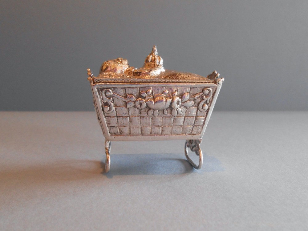 An Edwardian silver novelty snuff box crafted in the form of a miniature wicker cradle with a sleeping infant figure on the hinged lid. View III