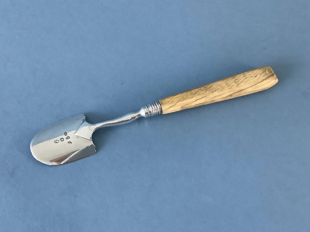 An antique Georgian sterling silver Stilton scoop featuring a spade-shaped hallmarked blade and a tapered smooth bone handle.