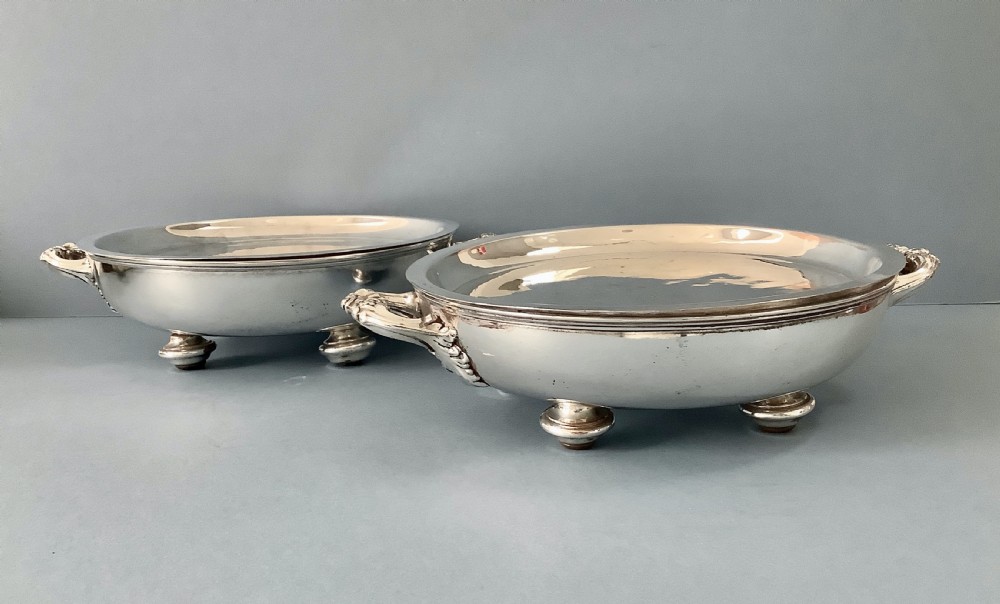 A pair of antique Georgian Old Sheffield Plate oval warming dishes with twin side handles and turned feet.