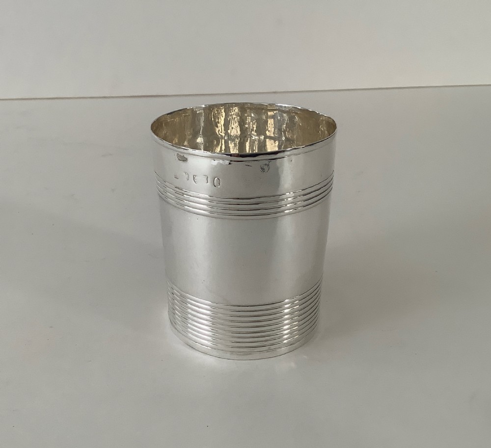 A cylindrical sterling silver beaker featuring horizontal reeded bands around the upper and lower exterior.