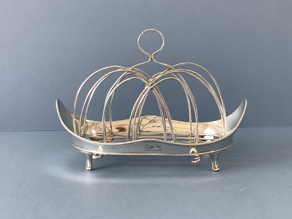 An antique Georgian silver toast rack with wire arch dividers displayed separately beside its footed oval frame. View VII