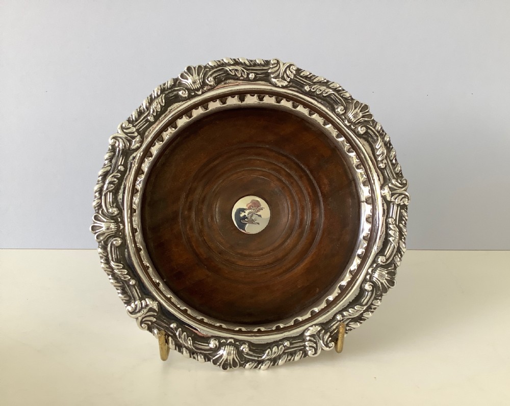 A pair of George III silver wine coasters featuring gadrooned rims with shell detailing, turned mahogany bases, and central silver bosses. View II