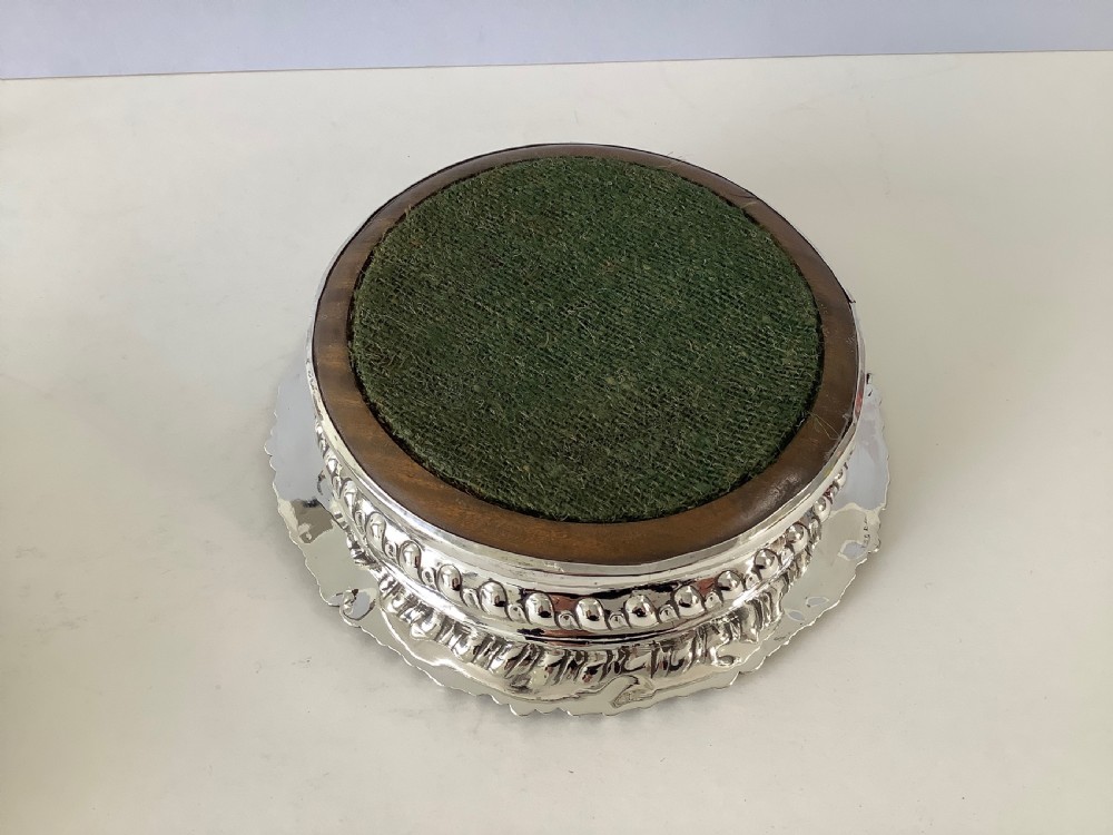 A pair of George III silver wine coasters featuring gadrooned rims with shell detailing, turned mahogany bases, and central silver bosses. View V