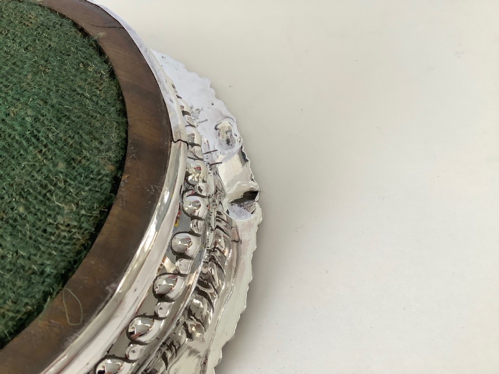 A pair of George III silver wine coasters featuring gadrooned rims with shell detailing, turned mahogany bases, and central silver bosses. View VI