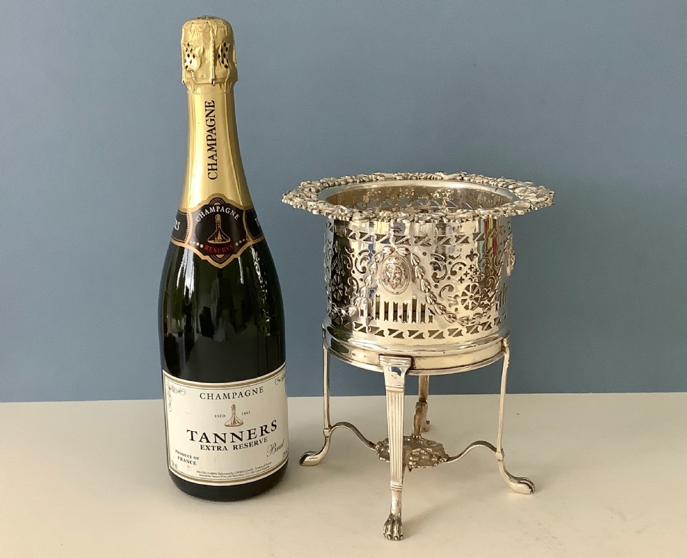 An antique silver-plated elevated wine coaster featuring pierced reticulated sides, a lion mask medallion, and tripod legs ending in claw feet. View II