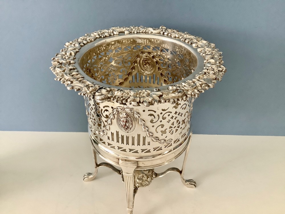An antique silver-plated elevated wine coaster featuring pierced reticulated sides, a lion mask medallion, and tripod legs ending in claw feet. View VII