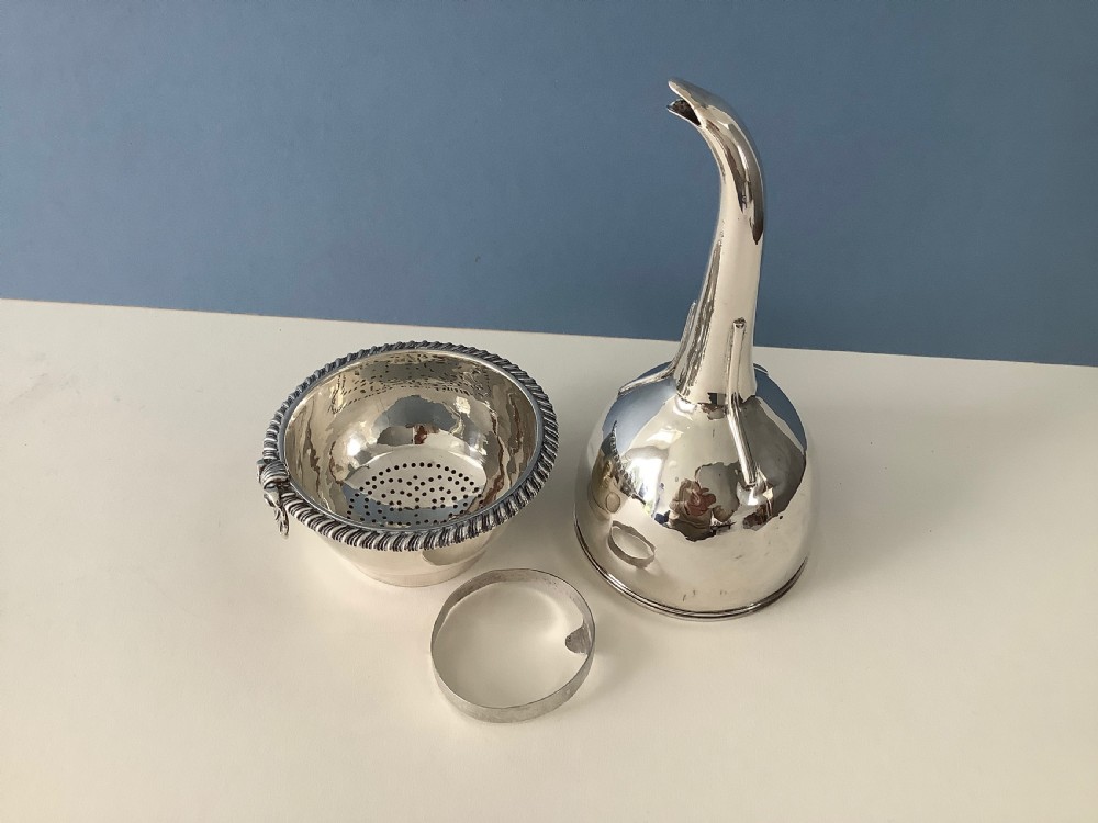 A three-part Georgian solid silver wine funnel featuring a perforated bowl with gadrooned rim, a retaining ring, and a curved spout.