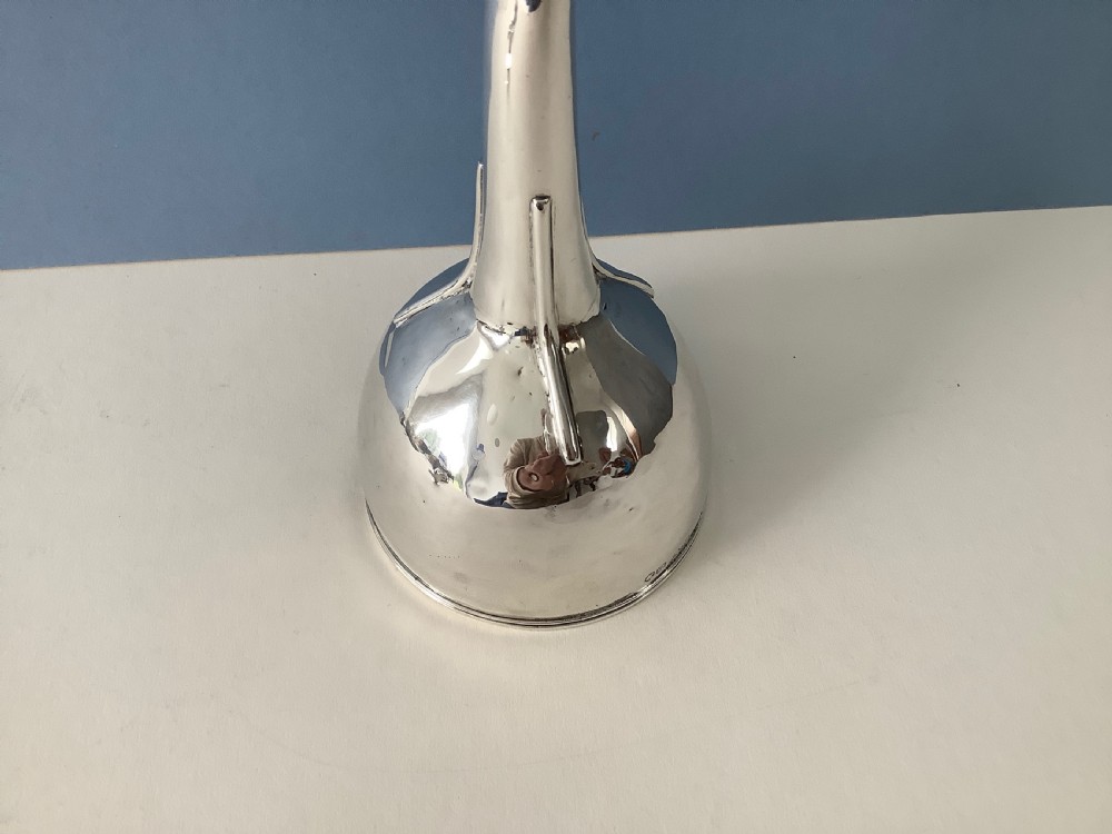 A three-part Georgian solid silver wine funnel featuring a perforated bowl with gadrooned rim, a retaining ring, and a curved spout. View V