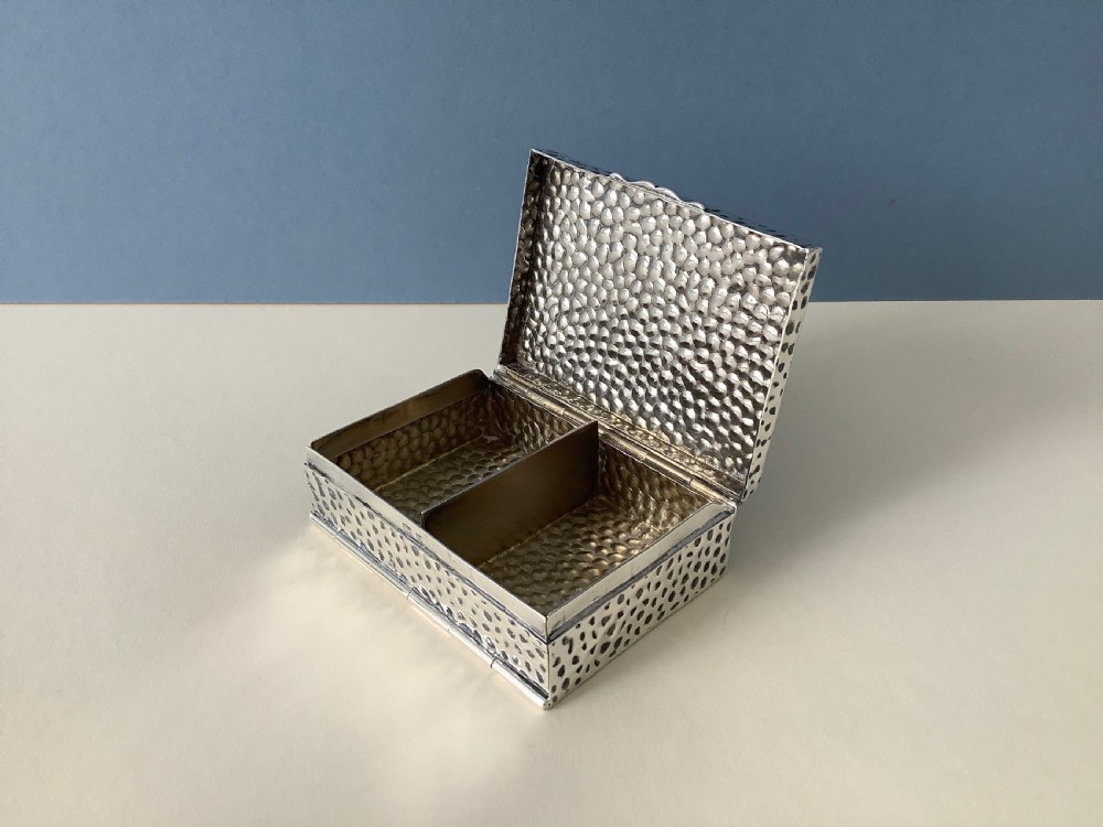 A hammered silver playing card box displayed open with two decks of illustrated playing cards inside. View III