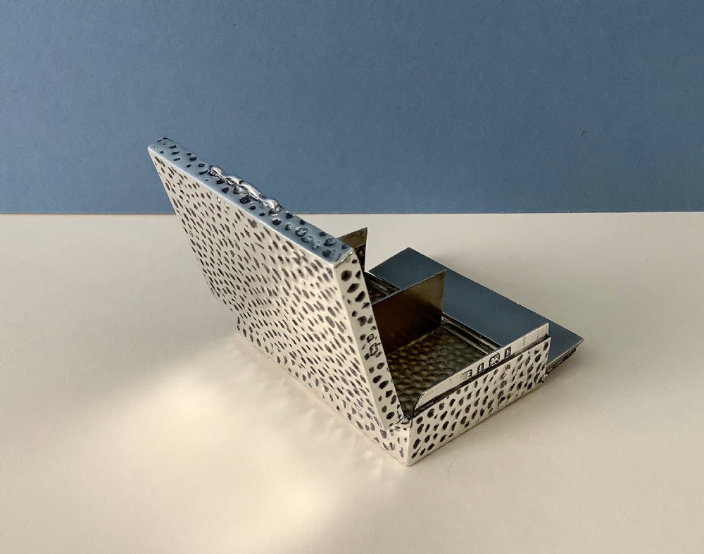 A hammered silver playing card box displayed open with two decks of illustrated playing cards inside. View V