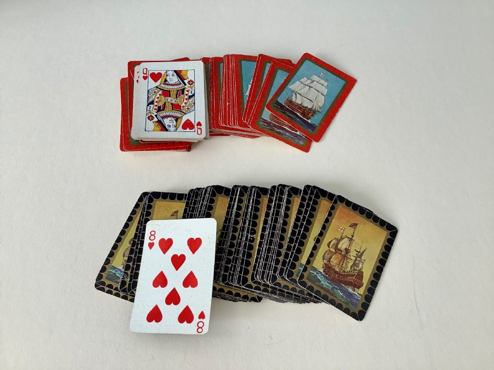 A hammered silver playing card box displayed open with two decks of illustrated playing cards inside. View VI