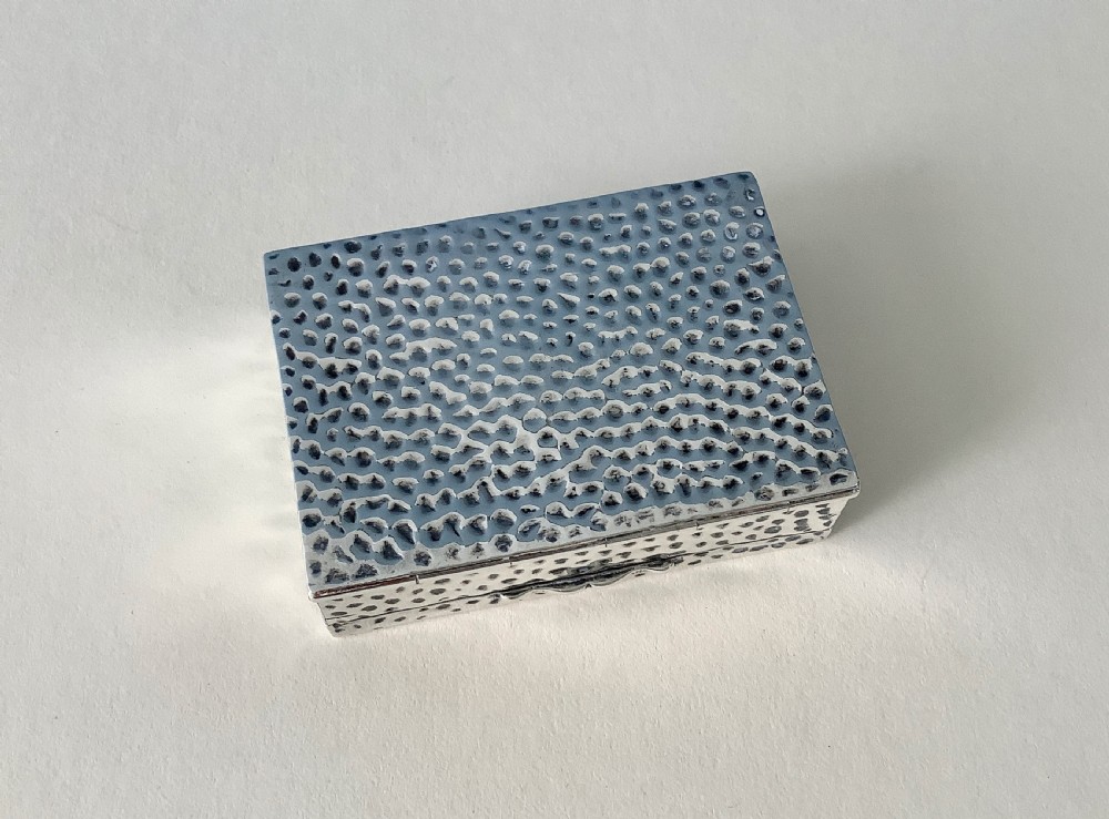 A hammered silver playing card box displayed open with two decks of illustrated playing cards inside. View VIII
